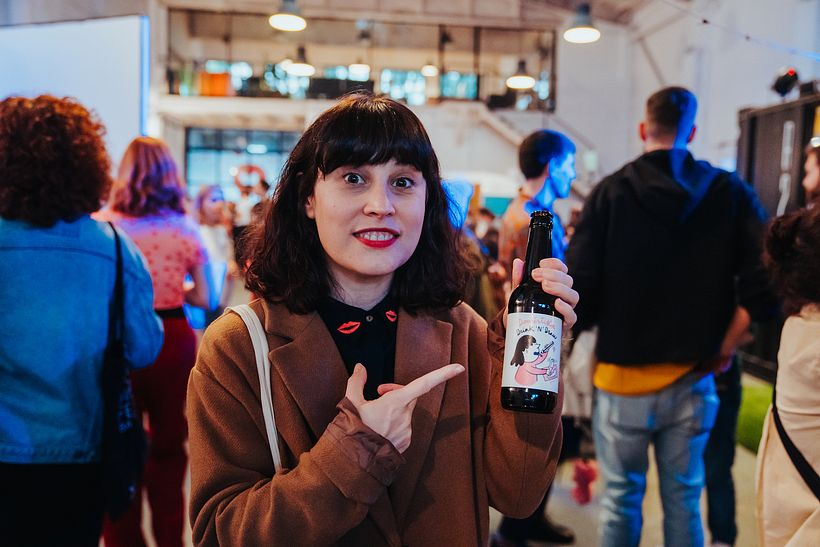 La ilustradora Lyona Ivanova mostrando la etiqueta de cerveza diseñada por ella.