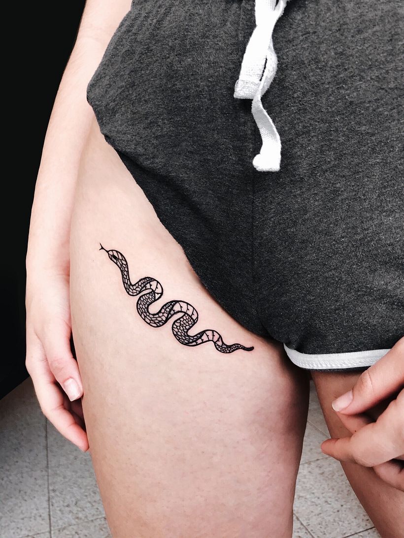 Autotatuaje de una serpiente en el muslo. 
