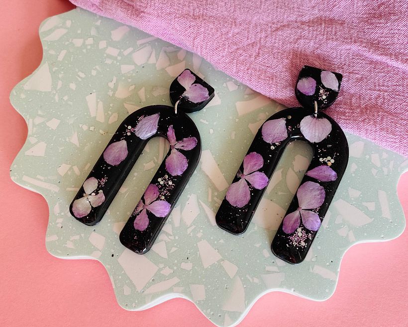 Self dried Hydrangea flowers with glitter and a black pigment background.