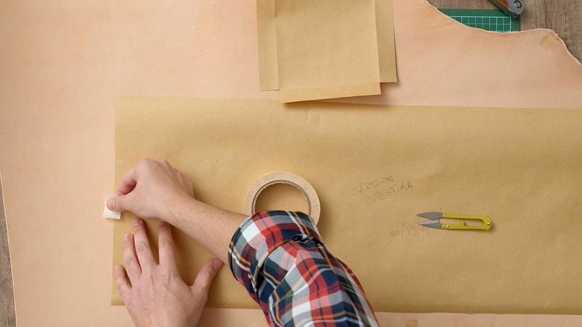Hold the pattern in place on the leather with bits of tape