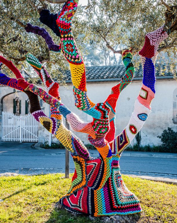 Intervenção de yarn bombing em uma árvore, Adobe Stock.