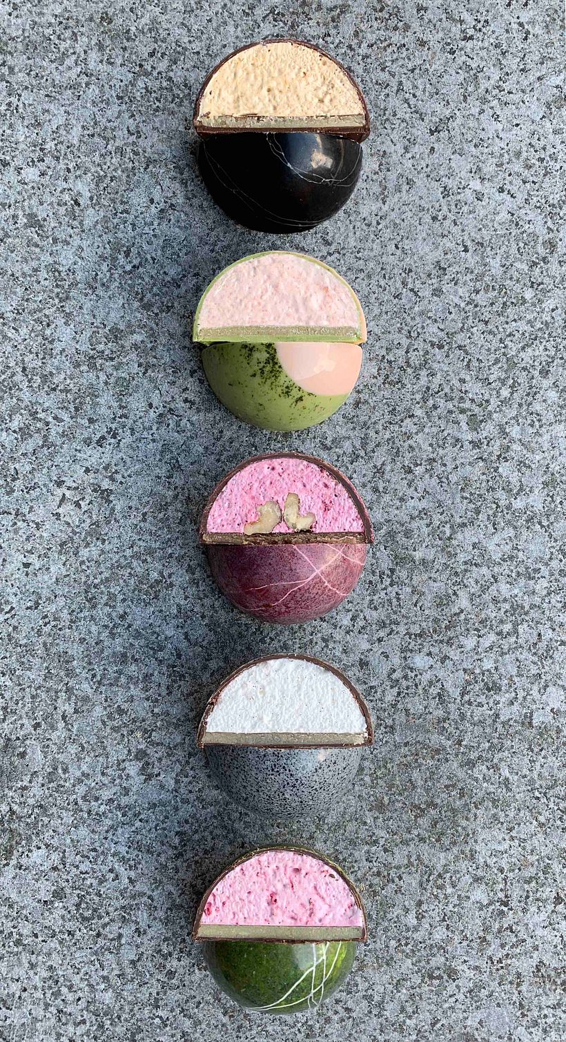 Cut open domes with italian meringue and marzipan base encased in chocolate 