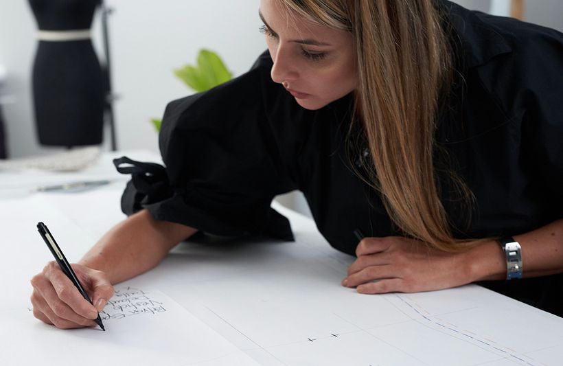 Natalia Londoño working on a pattern, a paper template to copy on the fabric.