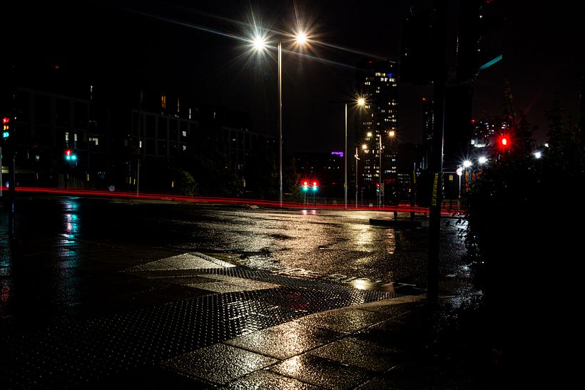 Traffic lights lit, a light of trail from a moving object and street lights creating starlights. Photo by Debbie Castro.