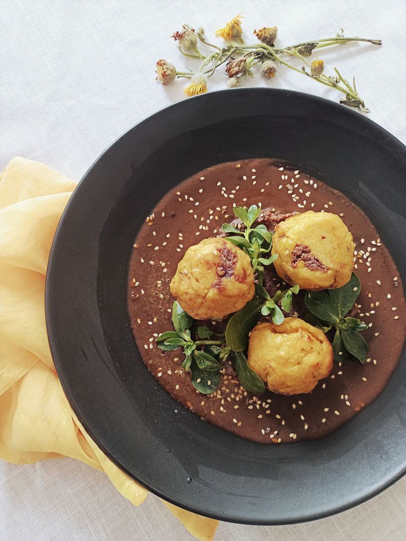 Tortitas de plátano macho rellenas de frijol en mole