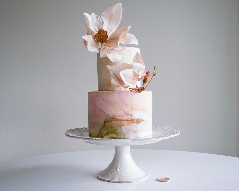 2-tiered minimalistic and colourful fondant with handcrafted sugar magnolias. What do you see in the bottom tier? 🕊