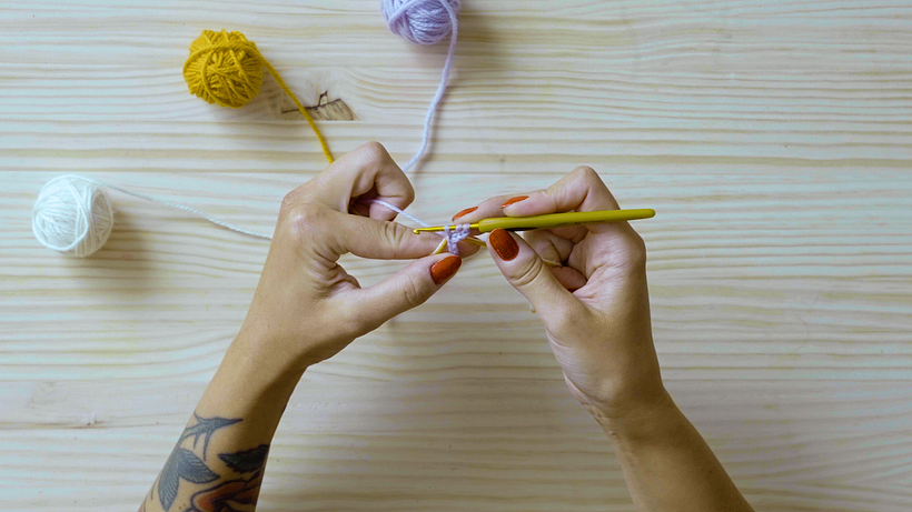 Loop all three yarns over the hook, pull the lilac yarn through the stitch, and you should end up with 3 hoops on your hook