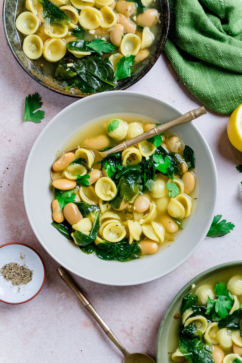 A healthy, vegan noodle soup with spinach, beans and lemon with colours that are close to each other on the color wheel.