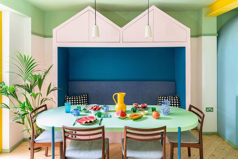 Comedor de planta abierta con banco rosa y azul a medida.