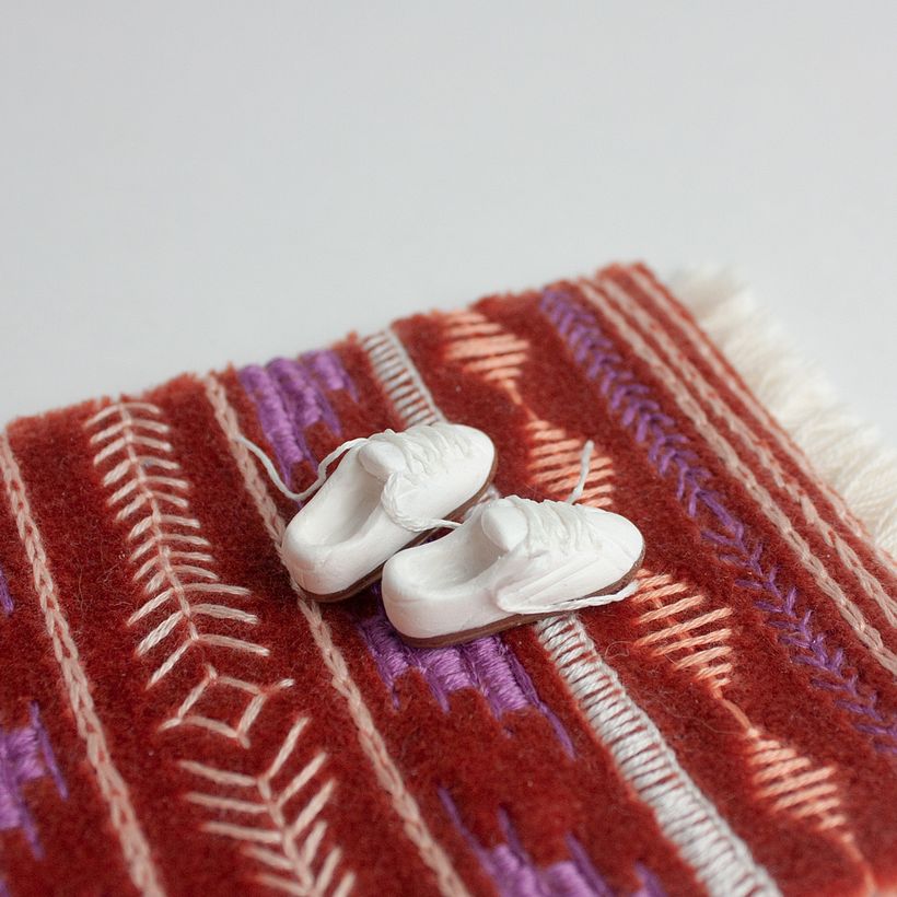 Kilka trampek na rdzawo-czerwonym dywanie.