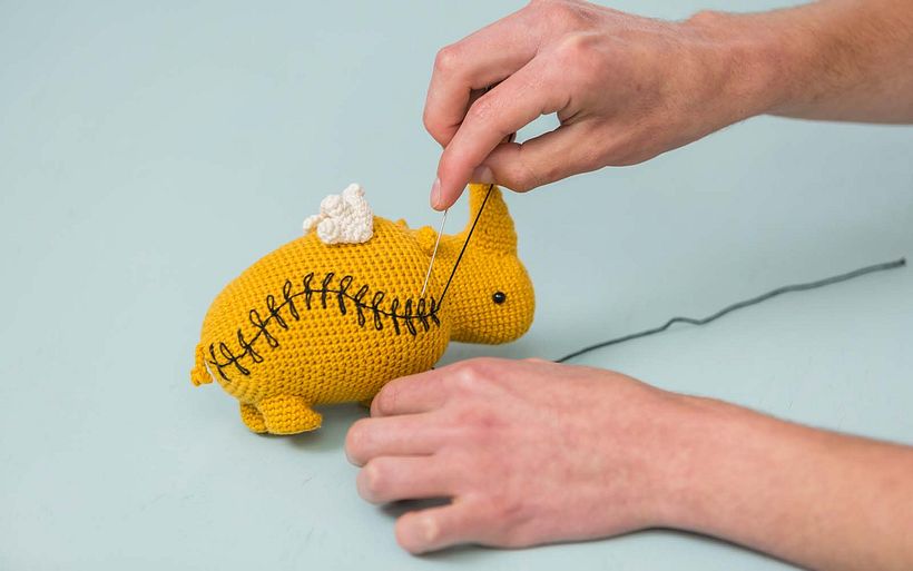 Marcelo decora su rinoceronte amigurumi con unas puntadas finales. 