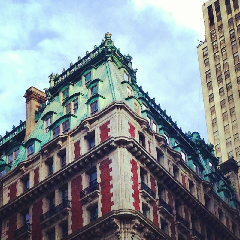 Cooper roof, brick facade, thick walls and iron balcony rails in NYC.
