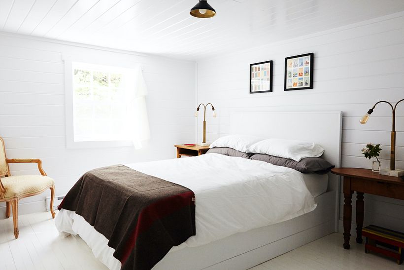 Paneled wood walls in the bedroom received a coat of white paint to create a peaceful bedroom.