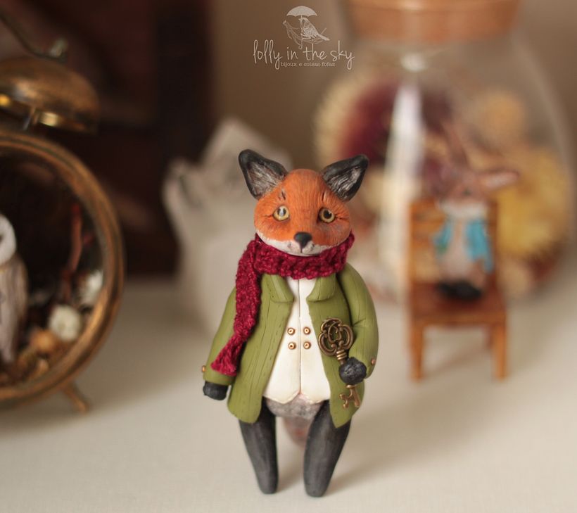 Escultura de raposa antropomorfizada, feita artesanalmente com polymer clay. cachecol em lã e chave em metal. 8 cm de altura 