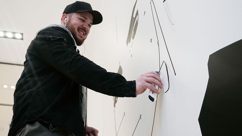 Nicolas Lawin taping a portrait-mural