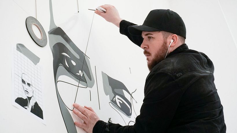 Nicolas Lawin taping a portrait-mural