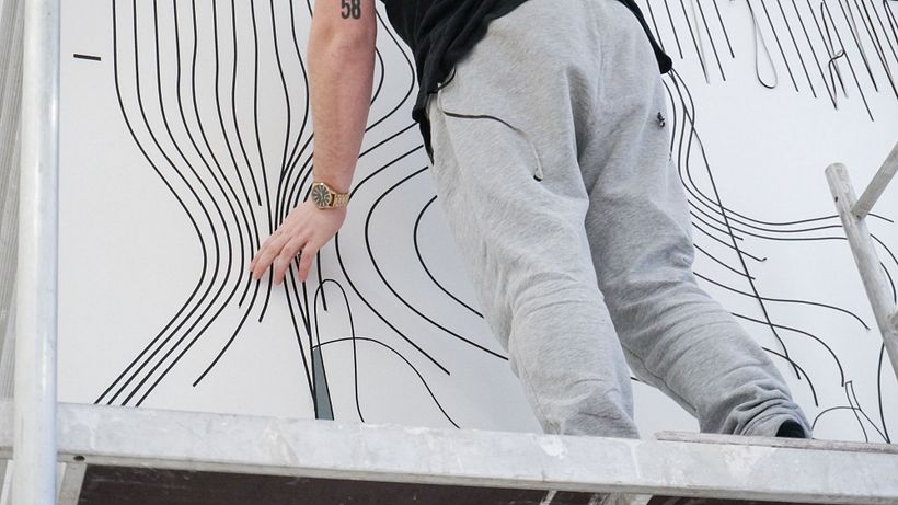Nicolas Lawin taping a portrait-mural