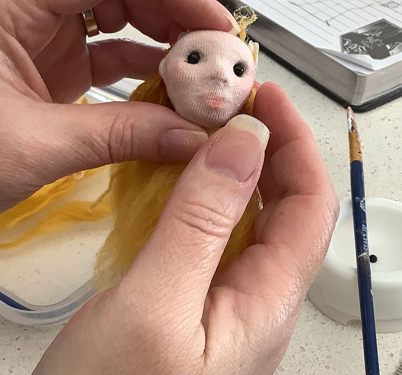 I used acrylic knitting wool brushed out with a pet brush to create wefts which I stuck to the head to make hair