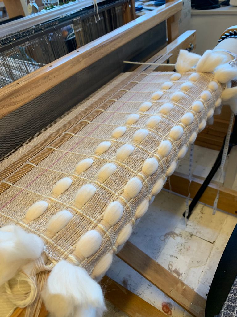 A work in progress shot. Notice how wide the fabric is before it is removed from the loom and washed.