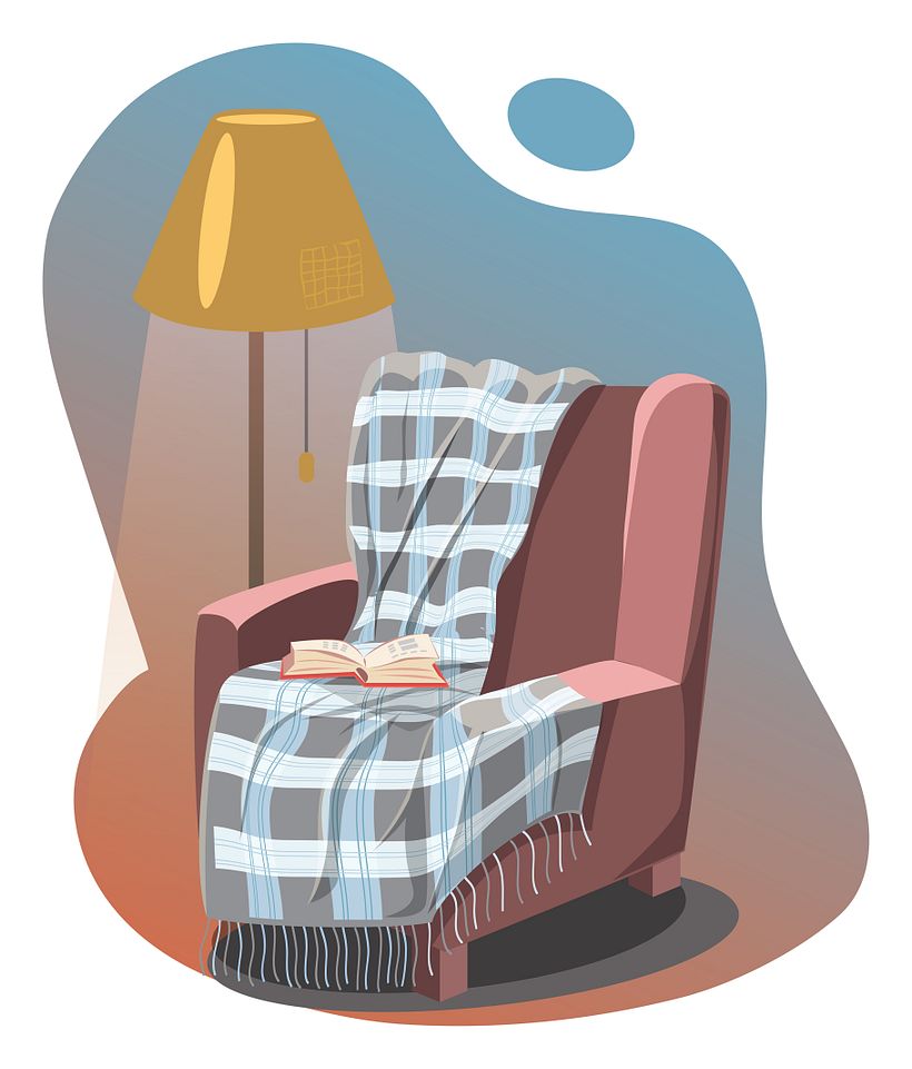 An armchair with plaid and book highlighted with a lamp