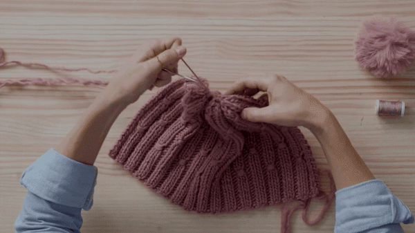 With an invisible seam, join the ends of the fabric and add a pompom as a finishing touch.