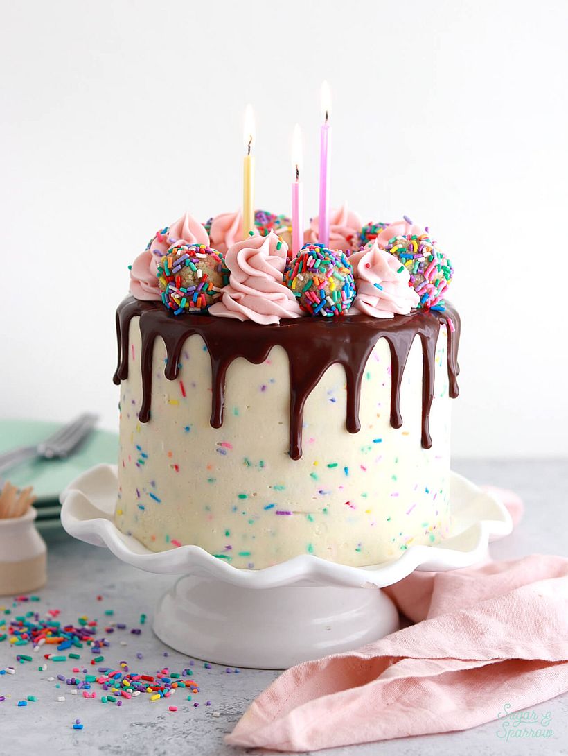 funfetti cake with funfetti buttercream, a chocolate ganache drip, and sprinkle cake truffle toppers