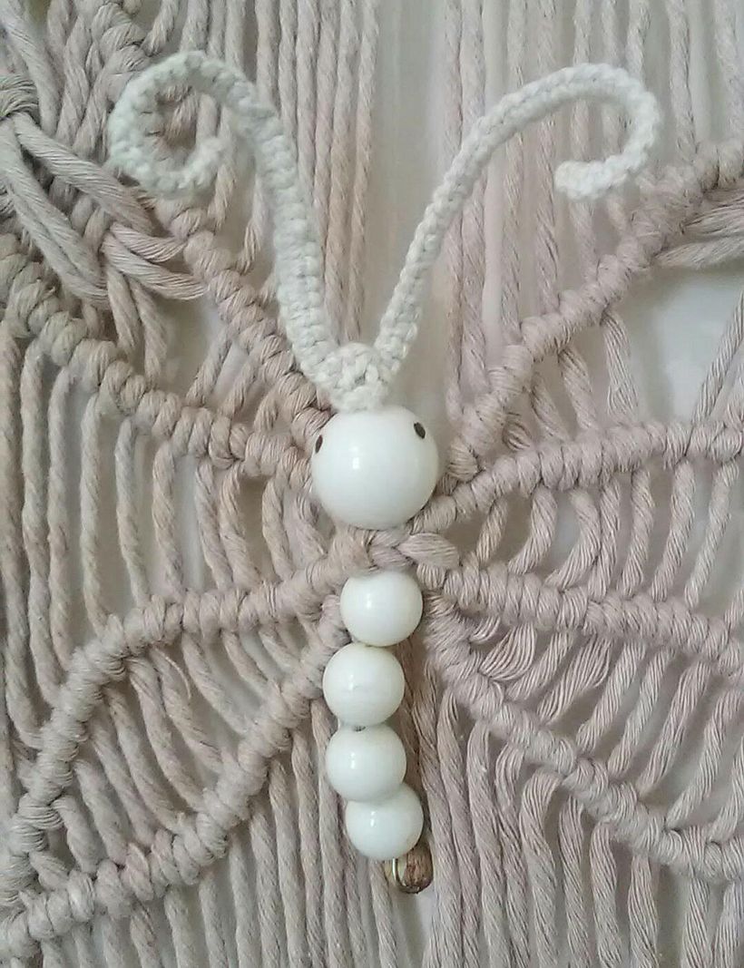 un papillon avec des perles en plastiques et bois sur un fil de fer très souple
