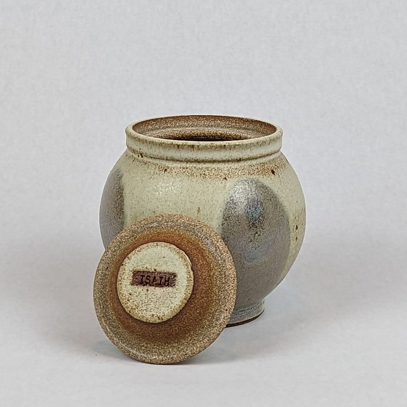 Lidded jar with "pink hills" glaze decoration. Lid propped up to show underside.