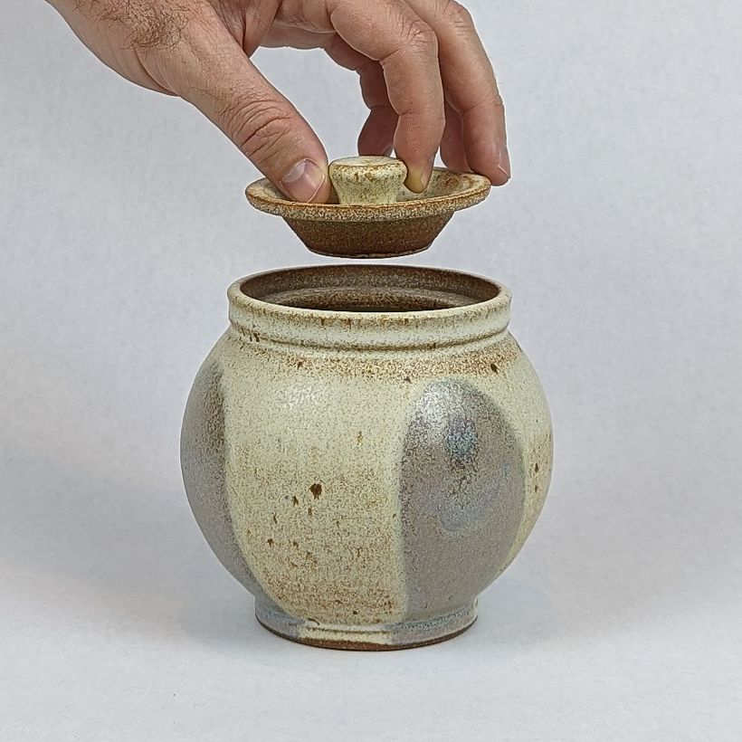 Lidded jar with "pink hills" glaze decoration. Hand showing sclale, as well as function of the knob of the lid.