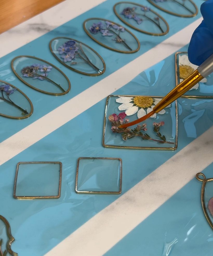 I used a quick swipe of a torch to pop all the bubbles and laid the flowers into the bezels onto the epoxy resin