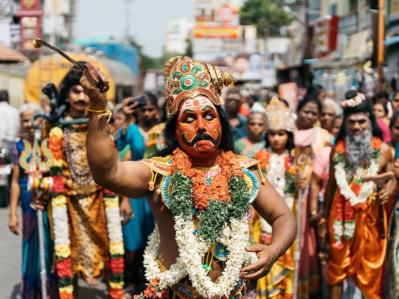 A man in disguise of Maduraiveera (Security God) dancing on the streets with other devotees in disguise of Gods.